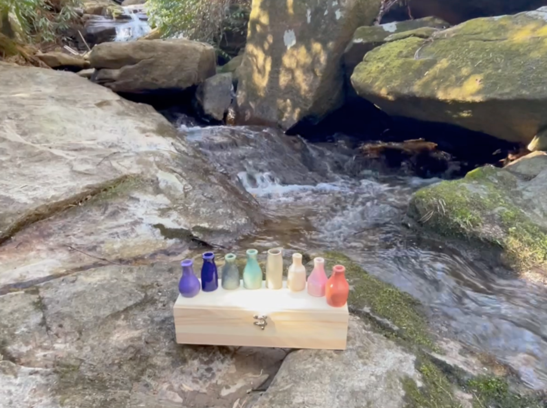Colorful Cedarleaf mini bottles beside a mountain creek