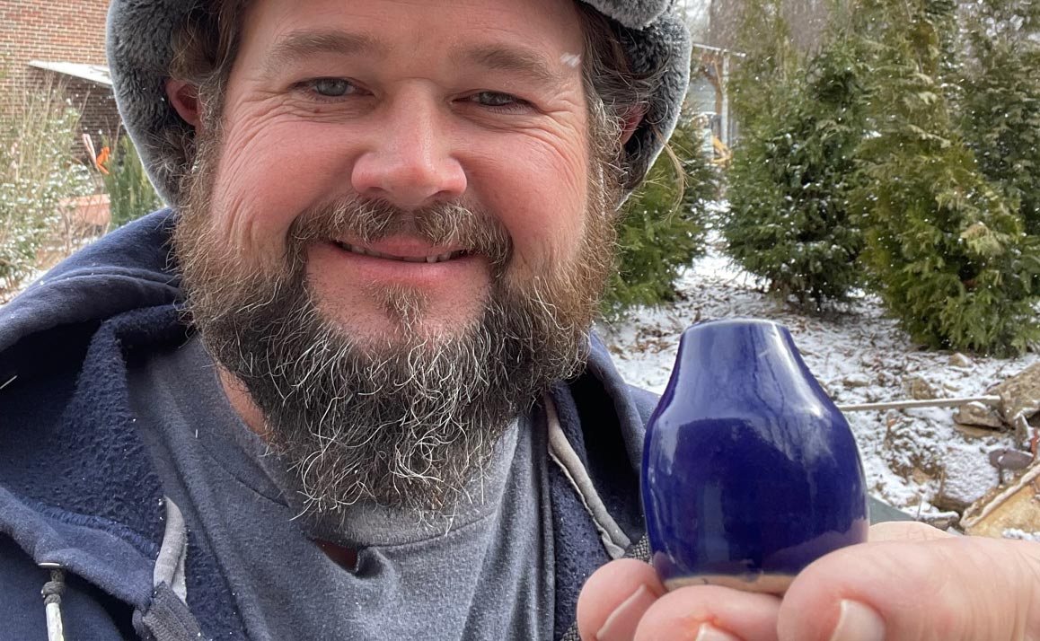 Nick Cedarleaf holding a blue ceramic bottle